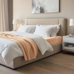 Prześcieradło jersey z elastanem w kolorze różowym, z gumką, rozłożone na materacu w sypialni. Sprzęt widoczny z boku, na tle jasnej pościeli i koców w neutralnych odcieniach. Stosowane w nowoczesnym wnętrzu z naturalnym oświetleniem.