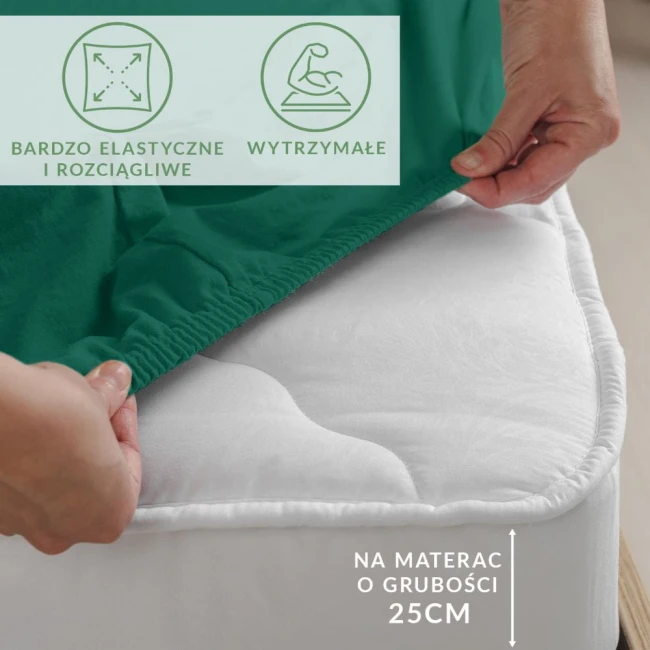 Prześcieradło jersey z elastanem w kolorze zielonym, rozłożone na materacu o grubości 25 cm, z widoczną gumką zabezpieczającą. Ujęcie z boku podkreśla elastyczność materiału. Napis informujący o dopasowaniu do materaca.