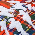 Poszewka dekoracyjna 45x45 cm w czerwonym wzorze w kratę z białymi, wypukłymi motywami choinek. Produkt leży na płaskiej powierzchni, ukazując szczegóły tekstury oraz kontrastujące kolory.