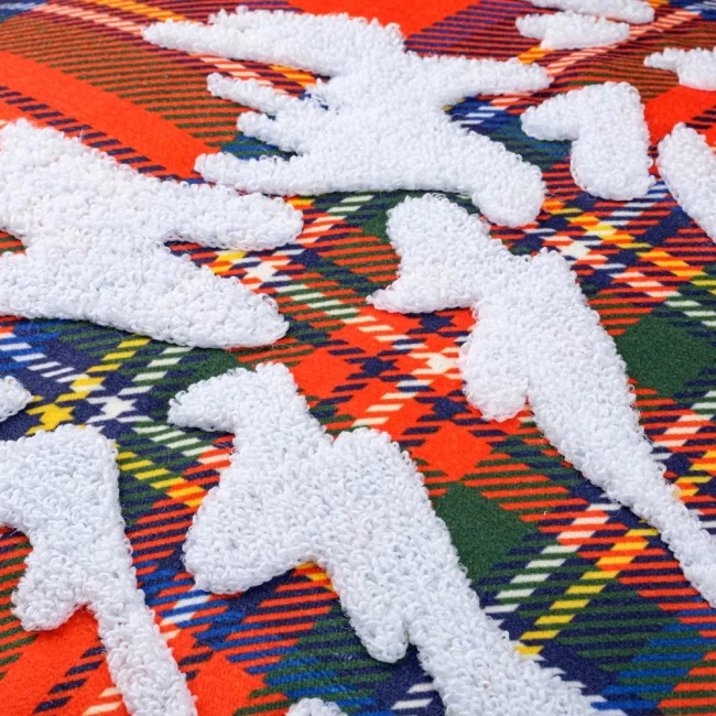 Poszewka dekoracyjna 45x45 cm w czerwonym wzorze w kratę z białymi, wypukłymi motywami choinek. Produkt leży na płaskiej powierzchni, ukazując szczegóły tekstury oraz kontrastujące kolory.