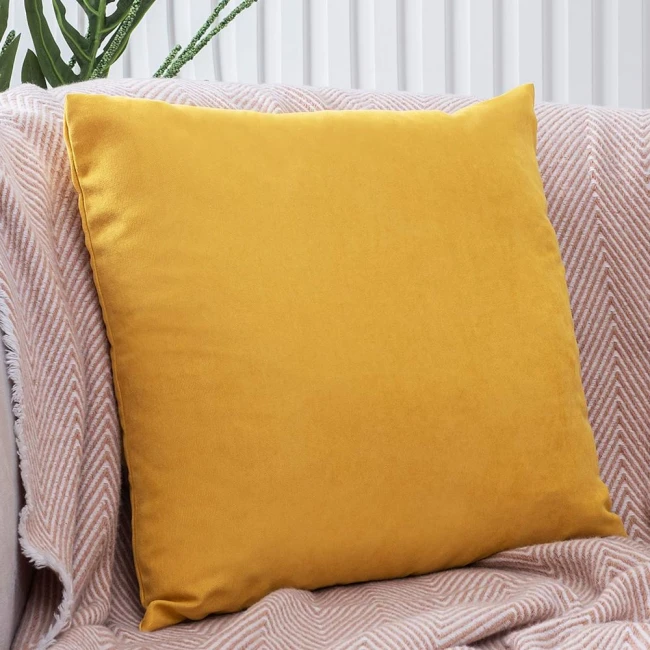 Poszewka dekoracyjna 40x40 cm w kolorze żółtym, gładka, wykonana z miękkiego materiału. Produkt leży na beżowym tle z widocznym wzorem, co podkreśla jego kolor. Ujęcie frontalne, ukazuje całe poduszki bez dekoracji.