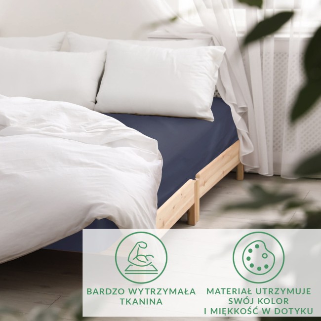 Prześcieradło satynowe bez gumki w kolorze ciemnego granatu, leżące na łóżku z białą pościelą. Widoczna gładka, błyszcząca tkanina podkreślająca elegancki wygląd. Tło jasne, surowe drewno. Pościel w białym kolorze stworzona do aranżacji sypialni.