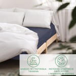 Prześcieradło satynowe bez gumki o wymiarach 200x220 cm w kolorze ciemnego granatu, z rozłożonymi białymi poduszkami na łóżku. Tkanina gładka, matowa, widoczna na drewnianym stelażu. Proste tło w jasnym wnętrzu.