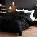 Poszewka satynowa 70x80 w kolorze czarnym, leżąca na łóżku z poduszkami; materiał o gładkiej fakturze, bez wzorów; otoczenie minimalistyczne, z lampami i rośliną w tle. Widzoczny również czarny koc na pościeli.