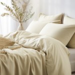 Poszewka satynowa 70x80 w kolorze kremowym, leżąca na łóżku z poduszkami, gładka tekstura, złożona na narzucie. Tło jasne, minimalistyczne, z dodatkiem roślinności w wazonie i filiżanką.