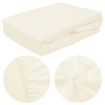 Prześcieradło frotte z gumką w kolorze ecru, rozmiar 180x200 cm, leżące na białym tle. Materiał z przyjemną, miękką fakturą; widoczne gumki wszyte na brzegach, które pozwalają na łatwe dopasowanie do materaca. Zbliżenia na detal strukturę tkaniny.