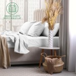 Prześcieradło frotte z gumką o wymiarach 70x140 cm w kolorze białym, rozłożone na łóżku, z widocznymi poduszkami. W tle delikatne dodatki, jak wazon z suszonymi kwiatami na stoliku. Tło neutralne, jasne.