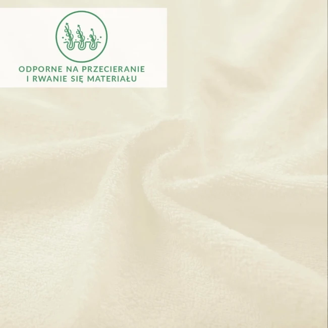 Prześcieradło frotte z gumką w kolorze ecru, o gładkiej i przyjemnej fakturze, leżące na jednolitym tle. Wykonane z trwałego materiału odpornego na przecieranie i rwanie. Widoczna jest na nim graficzna informacja o odporności materiału.