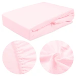 Prześcieradło frotte z gumką w kolorze różu kwarcowego, złożone na prostokątnej powierzchni. Widoczna gładka faktura materiału. W zbliżeniu detale gumki oraz splot tkaniny, ukazujące elastyczność i miękkość.