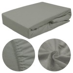 Prześcieradło frotte z gumką w kolorze szarym, leżące na płasko. Widać jego miękką, teksturowaną powierzchnię oraz elastyczny brzeg. Zbliżenie na gumkę pokazuje detale przylegania do materaca. Idealne dla rozmiaru 140x200 cm.