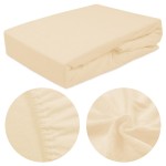 Prześcieradło frotte z gumką 140x200 w kolorze jasnego beżu, leżące na płaskiej powierzchni. Zbliżenie na teksturę materiału oraz elastyczną gumkę, podkreślającą dopasowanie. Tło proste, co ułatwia widoczność produktu.