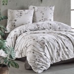 Pościel satyna bawełniana 160x200 w kolorze szaro-białym z delikatnym wzorem kwiatowym. Złożona na łóżku, widoczny pokrowiec na kołdrę i dwie poduszki. Tło w odcieniu szarości, rośliny w doniczce zapewniają naturalny akcent.