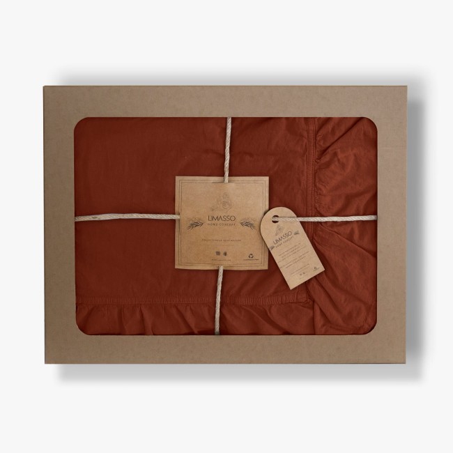 Pościel bawełniana z falbanką w kolorze ceglanym, o wymiarach 160x200, zapakowana w solidne, ozdobne opakowanie z tektury. Widoczne detale to subtelne falbanki oraz ręczna metka z logo producenta. Produkt leży na tle białego tła.