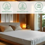 Ochraniacz na materac 60x120, pikowany, w kolorze białym, leżący na materacu w sypialni. Widoczne cechy to gładka faktura, estetyczne przeszycia oraz dopasowane boki.