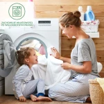 Matowa pralka otwarta z widocznym białym włóknem, a obok uśmiechająca się mama podaje dziecku ręcznik. W tle drewniane ściany, kosz z praniem. Obie osoby w piżamach, otoczenie domowe, ciepła atmosfera.