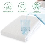 Ochraniacz na materac 140x200 w kolorze białym, z widoczną teksturą. Na zdjęciu widać szklankę z wodą, z której nalewa się ciecz, na materiał spływają kropelki wody.