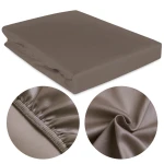 Prześcieradło satynowe 200x220 w kolorze sepia, leżące na płasko. Naciągnięte gumką, co zapewnia stabilność. Zbliżenia na teksturę materiału oraz elastyczną krawędź. Proste tło umożliwia łatwe dopasowanie do wnętrza.