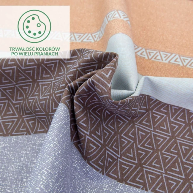 Pościel satyna bawełniana 160x200 w pomarańczowo-brązowe pasy z geometrycznymi wzorami, ukazana w zbliżeniu na detal. Tkanina o gładkiej fakturze, poszczególne elementy w układzie falistym. Widoczna etykieta z informacją o trwałości kolorów po praniach.