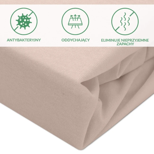 Ochronne prześcieradło z gumką 180x200 w kolorze beżowym, leżące na białym tle. Materiał o delikatnej fakturze. Widać informacje o właściwościach: antybakteryjny, oddychający, eliminujący nieprzyjemne zapachy, przedstawione w formie ikon.