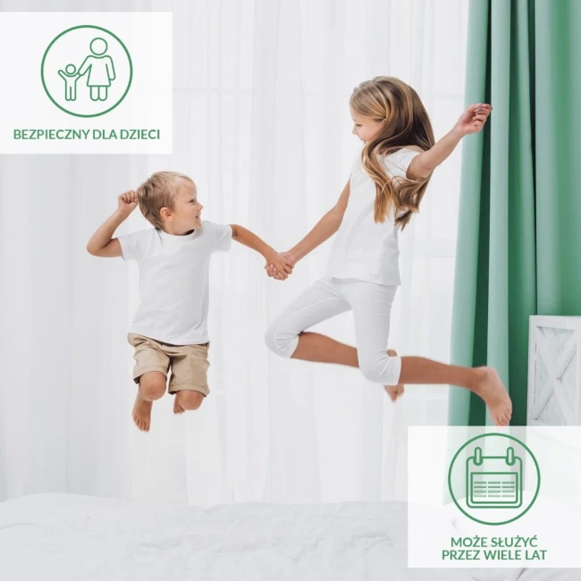 Ochronne prześcieradło z gumką 180x200 SMARTCEL w kolorze białym, leżące na łóżku. Na zdjęciu dzieci w białych t-shirtach skaczą na łóżku, w tle białe zasłony i zielona ściana, co podkreśla radosną atmosferę.