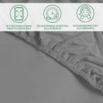 Ochronne prześcieradło z gumką w kolorze szarym, rozłożone, ukazujące wytrzymałą gumę obszernie wokół krawędzi. Zbliżenie na materiał, wskazujące na jego gładką fakturę i elastyczność, co zapewnia doskonałe dopasowanie do materaca.