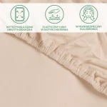 Ochronne prześcieradło z gumką w kolorze beżowym, z widoczną, wytrzymałą gumą obszytą dookoła. Materiał jest elastyczny i miękki w dotyku. Prześcieradło pokazane z bliska, leżące na jasnym tle.