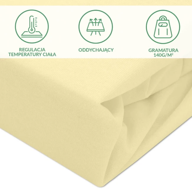 Ochronne prześcieradło z gumką 70x140 cm w kolorze kremowym, wykonane z oddychającego materiału. Ujęcie z boku, ukazuje złożony produkt z delikatną fakturą. Posiada informacje o regulacji temperatury ciała oraz gramaturze 140 g/m².