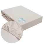 Ochronne prześcieradło z gumką 180x200, w kolorze popielatym. Produkt leży na jednolitym tle, z widocznym brzegiem gumki. Zbliżenie ukazuje teksturę materiału, co wskazuje na elastyczność i trwałość. W rogu widoczny delikatny nadruk.