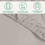 Ochronne prześcieradło z gumką 70x140 cm w kolorze popielowym, wykonane z miękkiego i elastycznego materiału. Gumka obszyta dookoła zapewnia stabilne mocowanie. Detal na zdjęciu pokazuje fakturę materiału i elastyczność gumki.
