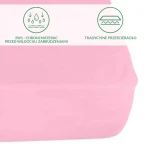 Ochronne prześcieradło z gumką w kolorze różowym, rozmiar 200x220 cm, leży na gładkiej powierzchni. Materiał wygląda na gładki, elastyczny, z widocznymi napisami informacyjnymi o funkcji ochronnej. Gumka zabezpiecza prześcieradło przed przesuwaniem.