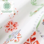 Pościel bawełniana 200x220 Cottonlove Exclusive Elyese w białym kolorze z kolorowymi wiosennymi kwiatami. Zdjęcie przedstawia fakturę materiału z wyraźnymi wzorami w odcieniach czerwieni, zieleni i fioletu. Ujęcie w zbliżeniu, eksponujące szczegóły.