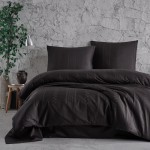 Pościel satyna bawełniana 160x200 w odcieniu szaro-czarnym, z geometrycznym wzorem. Widok frontalny, produkty rozłożone na łóżku. W zestawie poszewki na poduszki i kołdrę. Tło w odcieniu jasnoszarym, naturalne akcesoria dekoracyjne w otoczeniu.