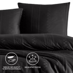 Pościel bawełniana 160x200 w geometrycznym wzorze w odcieniach szarości. Złożona, z widocznymi poszewkami. Materiał posiada delikatny połysk i jest miękki w dotyku. Ułożona na jednolitym tle. Grafika ikon w dolnym rogu przedstawia właściwości materiału.