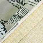 Pościel satyna bawełniana 220x200 Luxury Premium Greta w kolorze zielonym z dekoracyjnym wzorem liści. Zamek błyskawiczny na poszewce, delikatna faktura materiału, widoczna żółta tkanina w kropki. Produkt leżący, zbliżenie na detale.