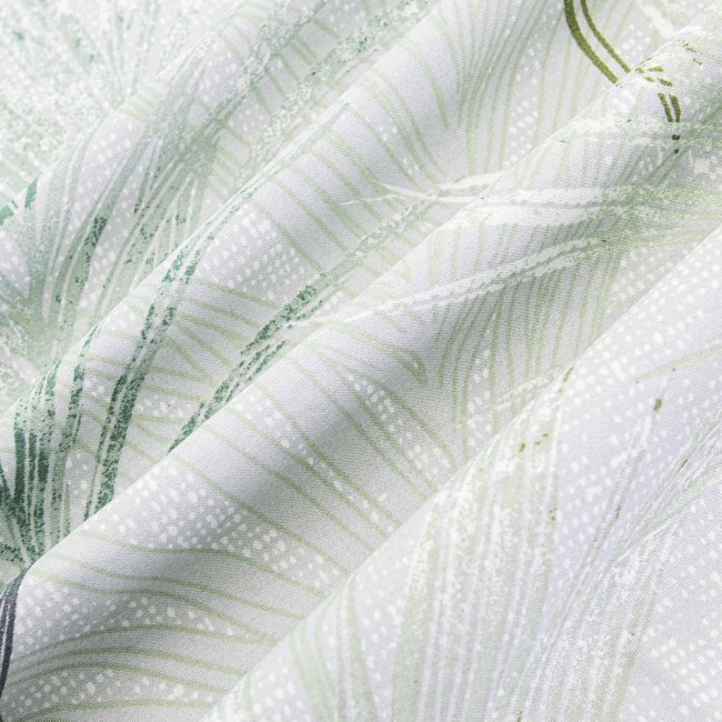 Pościel satyna bawełniana 220x200 w kolorze zielonym z dekoracyjnym wzorem liści, widoczna w leżącej pozycji. Tło jasne, pozwala na wyraźne pokazanie detali faktury materiału. Wzór w delikatne liście w odcieniach zieleni i bieli.