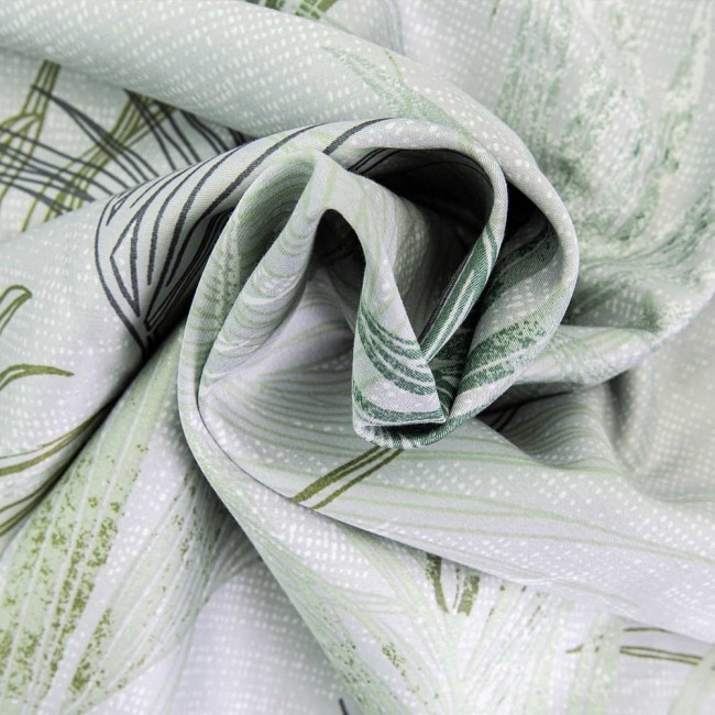 Pościel satyna bawełniana 220x200 w odcieniach zieleni z dekoracyjnymi liśćmi, złożona. Widoczne subtelne wzory na tle w jasnym odcieniu, tkanina gładka z połyskiem, idealna do stylizacji sypialni. Zblizenie na tkaninę ukazujące detale wzoru.