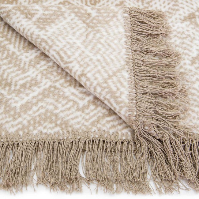 Koc bawełniany 150x200 cm w beżowo-żółto-pomarańczowy wzór z frędzlami. Widok zbliżeniowy na fragment koca leżącego, ukazujący teksturę i detale wzoru. Tło białe, podkreślające kolory materiału.