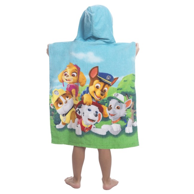 Ręcznik ponczo z kapturem 50x115 cm w kolorze błękitnym, z widocznymi postaciami z Psi Patrol, w kącie ujęcia z tyłu. Posiada nadruk na całej powierzchni, z miękkiej, chłonnej dzianiny. Produkt leży na nogach użytkownika, odsłaniając stopy.