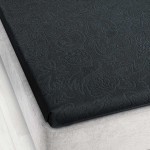 Prześcieradło żakardowe bez gumki w kolorze grafitowym, o wymiarach 175x220 cm, leżące na materacu. Widoczna faktura wzoru w formie delikatnych, stylizowanych roślin. Produkt prezentuje się na jasnym tle szarego materaca.