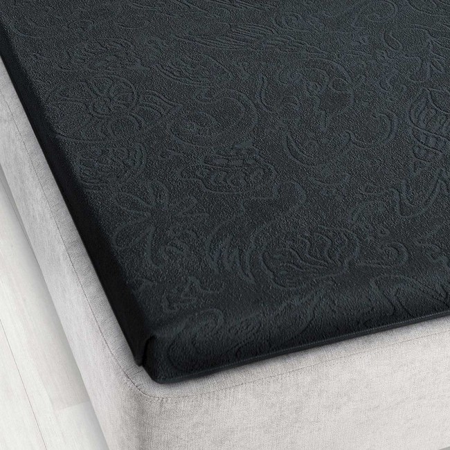 Prześcieradło żakardowe bez gumki w kolorze grafitowym, o wymiarach 175x220 cm, leżące na materacu. Widoczna faktura wzoru w formie delikatnych, stylizowanych roślin. Produkt prezentuje się na jasnym tle szarego materaca.