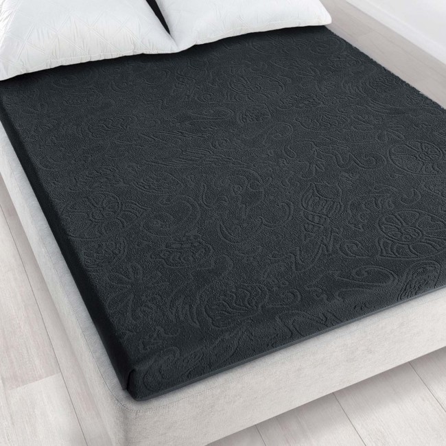 Prześcieradło żakardowe w kolorze grafitowym o wymiarach 175x220 cm, leżące na materacu. Produkt ma matową fakturę i subtelny wzór. Widoczne białe poduszki w tle na jasnym, jednolitym tle sypialni.