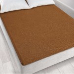 Prześcieradło żakardowe bez gumki w kolorze brązowym, o wymiarach 175x220 cm, leżące na spodniej stronie łóżka. Widoczny detal tekstury żakardowej, z subtelnym wzorem. Tło w jasnych odcieniach podłogi drewnianej, na którym znajduje się łóżko.