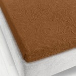 Prześcieradło żakardowe w brązowym kolorze, o wymiarach 175x220 cm, rozłożone na materacu. Tkanina ma delikatną teksturę i wzór, otula narożniki materaca. Tło zdjęcia jest jasne, co dobrze eksponuje produkt.