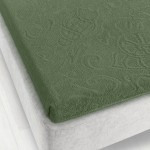 Prześcieradło żakardowe bez gumki w kolorze zielonym, z fakturą o wyraźnym splocie, leży na materacu o szarej obudowie. Widoczne jest jego przyleganie do krawędzi materaca w zestawieniu z jasnym, jednolitym tłem podłogi. Wymiary: 175x220 cm.