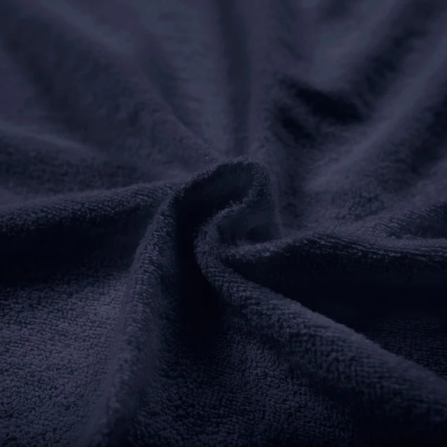 Poszewka frotte 40x40 w kolorze ciemnego granatu, o teksturze miękkiego materiału. Zbliżenie na fakturę tkaniny, ukazujące jej gęstość i sprężystość, leżąca na płaskiej powierzchni. Brak widocznych napisów lub logo.