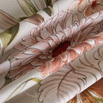 Pościel bawełniana 200x220 Cottonlove Exclusive Sidelya w beżowy wzór z kolorowymi kwiatami, złożona i lekko pofałdowana. Widać duże kwiaty w odcieniach różu, pomarańczy i zieleni, na gładkim tle.