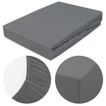 Prześcieradło jersey z gumką w kolorze szarym, w wymiarach 120x200 cm. Złożone i leżące na płaskiej powierzchni. Zbliżenie na gumkę i fakturę materiału w detalach. Gładka powierzchnia, bez wzorów, idealne do łóżka.