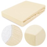 Prześcieradło jersey z gumką w kolorze kremowym, rozmiar 160x200 cm. Złożone, z widoczną elastyczną gumką do mocowania. Zbliżenie na fakturę materiału oraz detal brzegu, przedstawiający wykończenie. Proste tło, podkreślające kolor i fakturę.