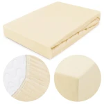 Prześcieradło jersey z gumką 60x120 w kolorze kremowym, leżące, z widokiem na gładką fakturę materiału. Zbliżenie na gumkę wzdłuż brzegów oraz detal narożników. Produkt na białym tle, idealny do łóżeczek dziecięcych.