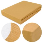 Prześcieradło jersey z gumką 200x220 w kolorze musztardowym. Leżące na płaskiej powierzchni, z widocznymi detalami gumki w białej tkaninie. Zbliżenie na krawędź prześcieradła. Prezentuje teksturę dzianiny, bez dodatkowych zdobień.